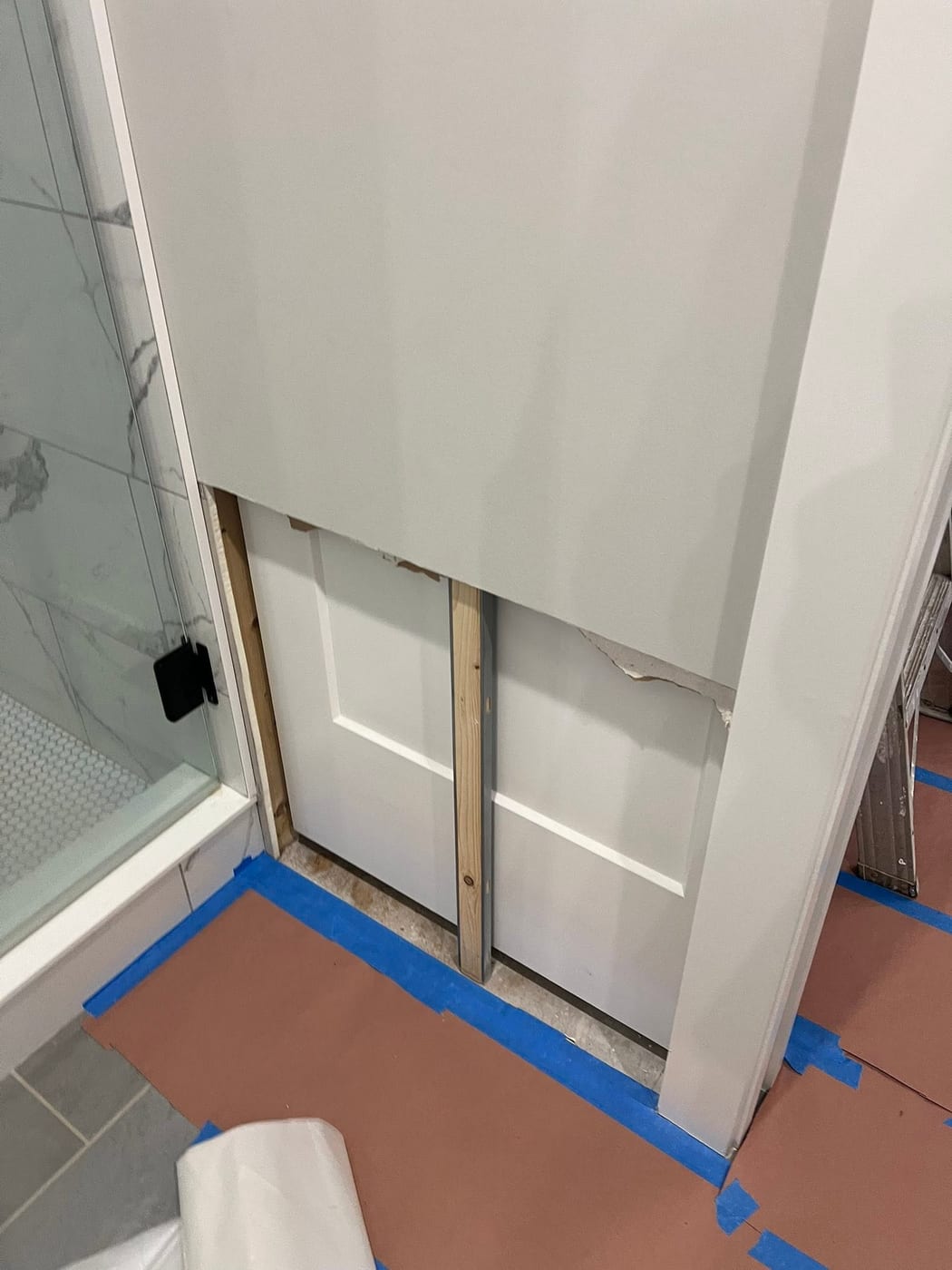 Pocket door framing with open stud wall and partial drywall beside the shower