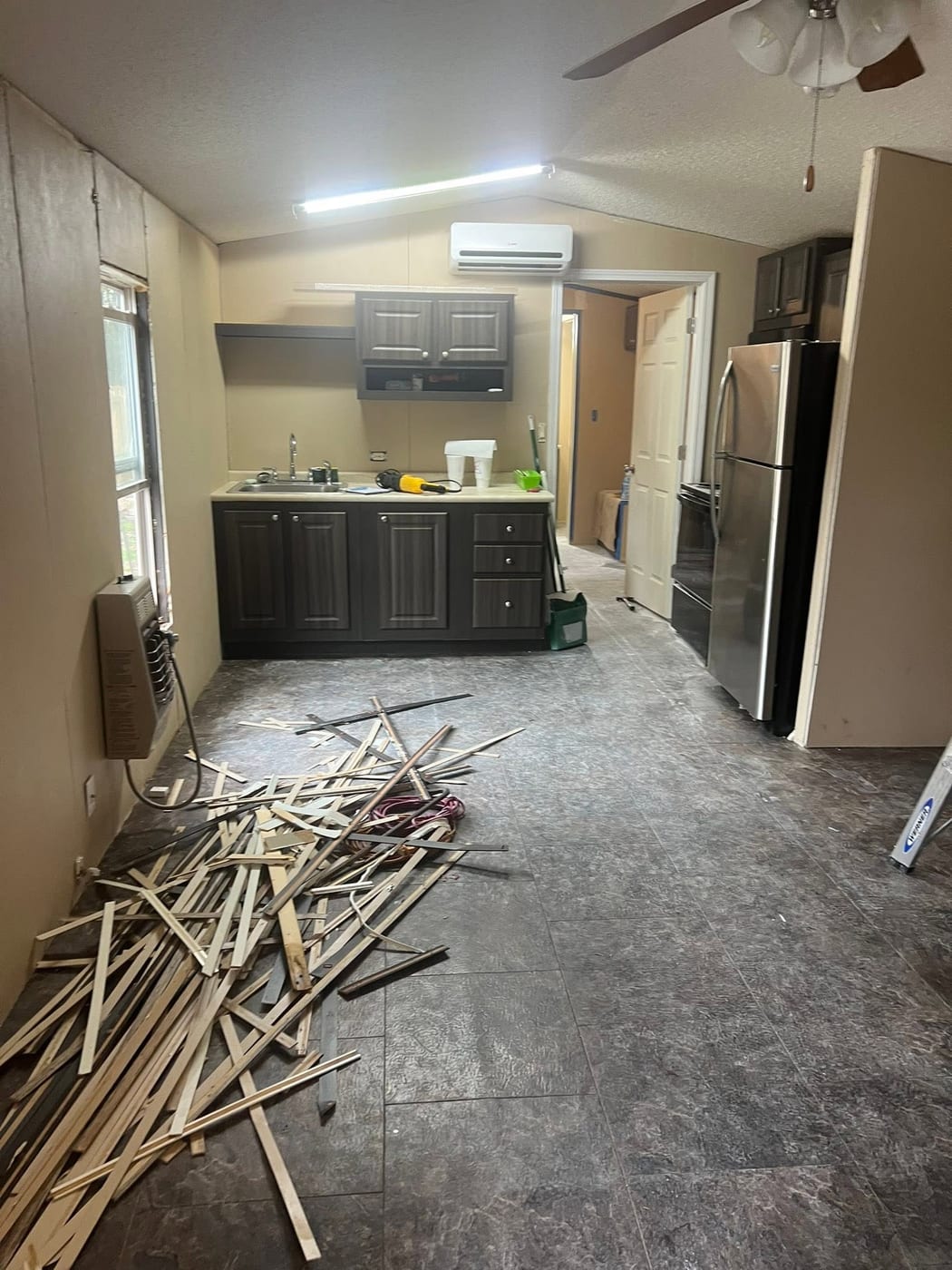 Kitchen interior during remodel with trim debris on the floor and tools on the counter